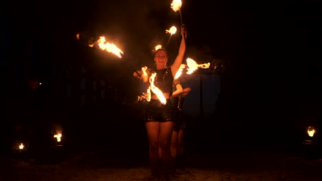 A-group-of-people-with-fire-and-torches-dancing-at-sunset-in-the-hangar-in-slow-motion.-Fire-show.